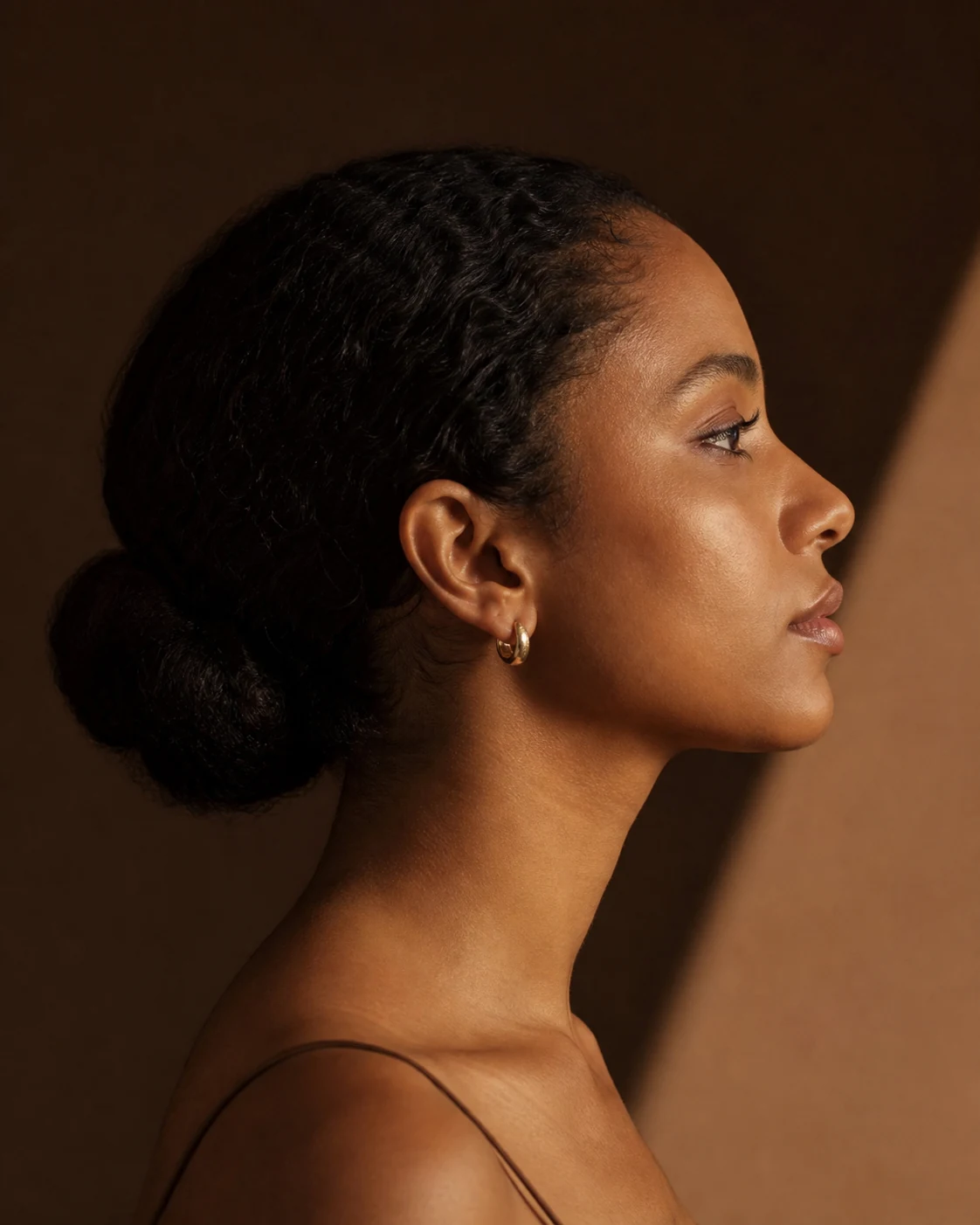 Mulher negra de perfil em retrato editorial que valoriza o contorno nasal